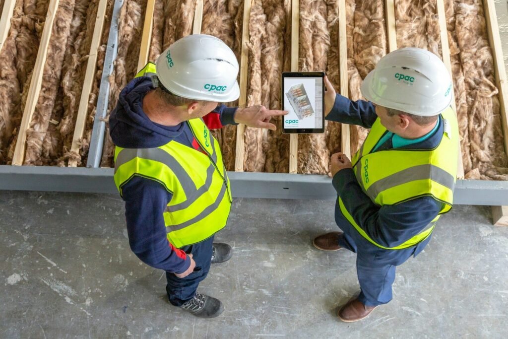 Two construction workers review plans on a tablet