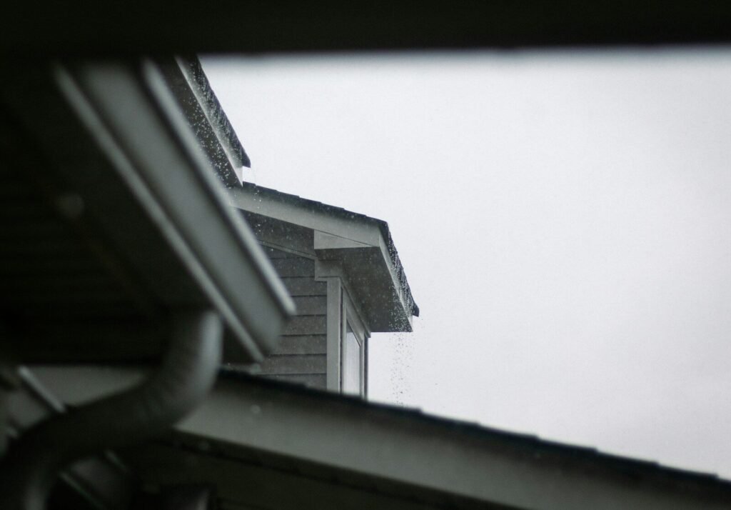 A house roof and gutter system against a grey sky