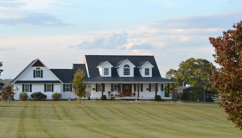 A large white farmhouse with a wrap-around porch