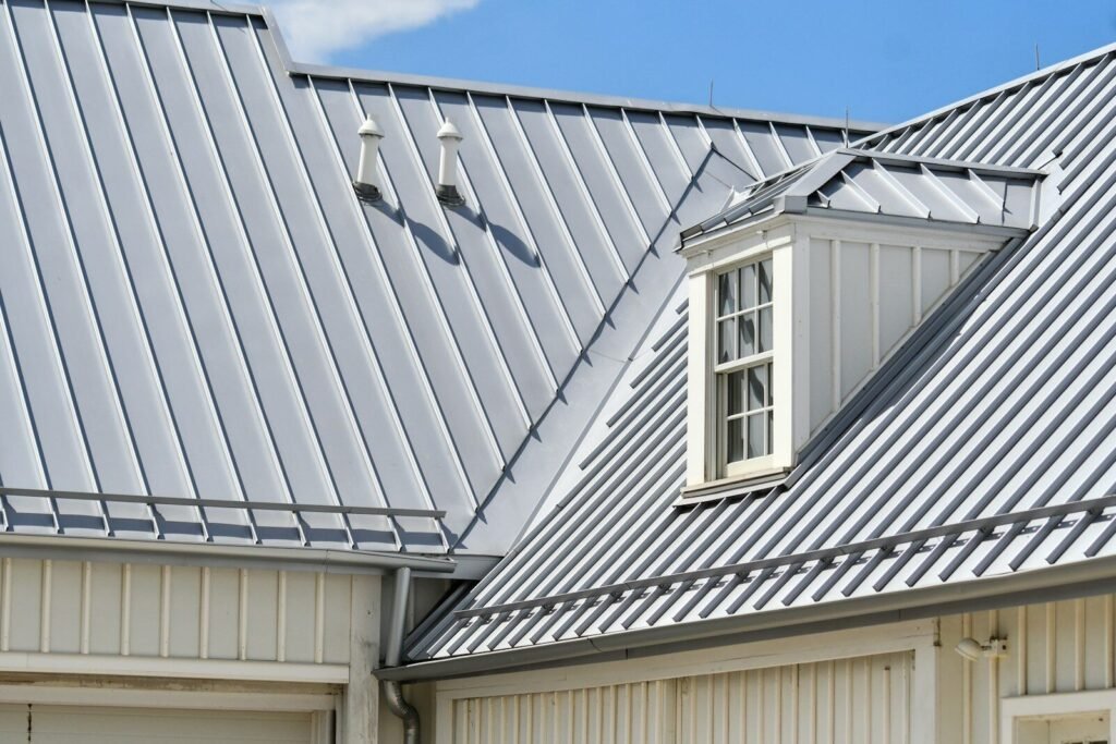 Grey metal roof, white siding, and a dormer window